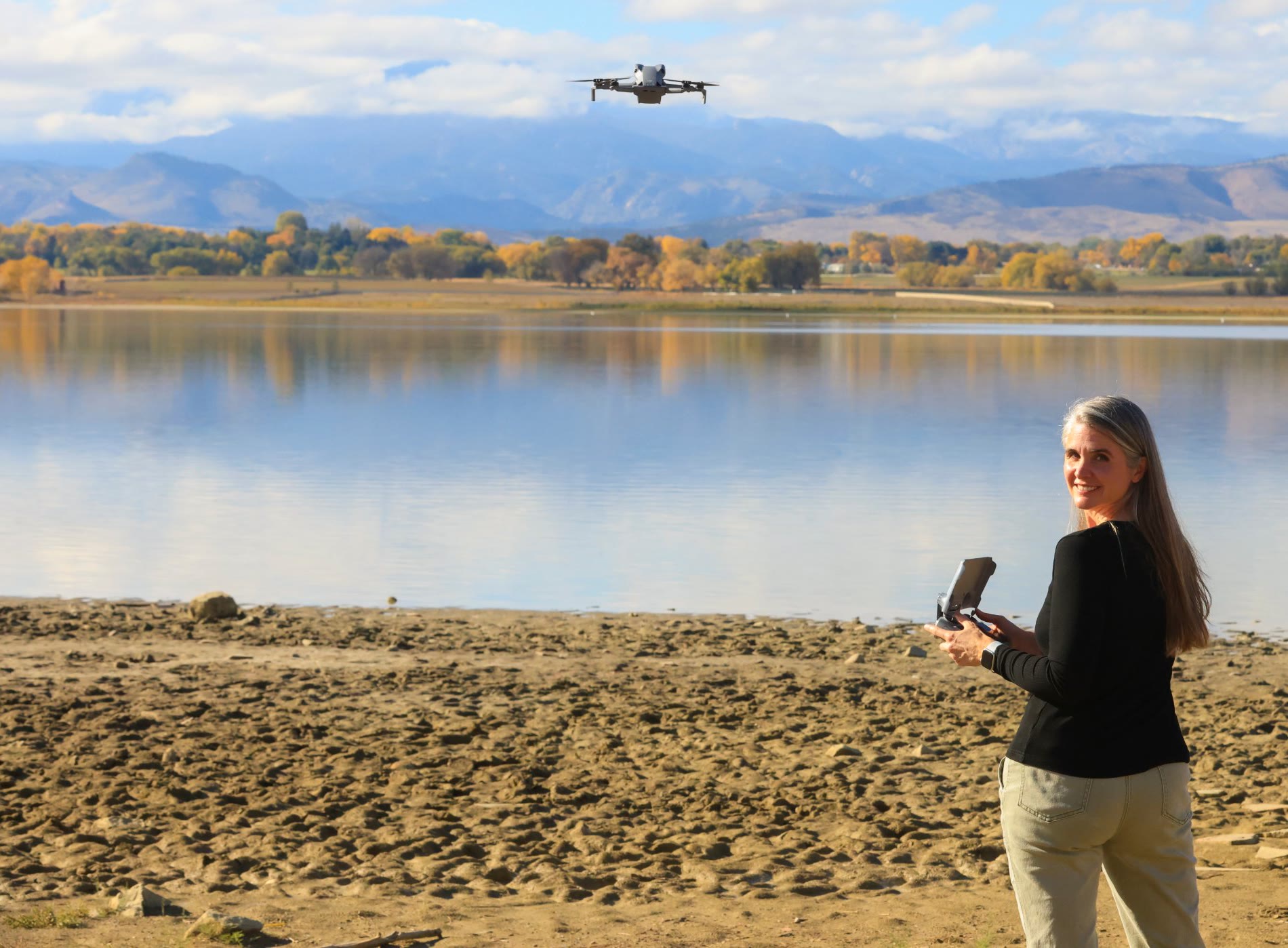 Kyra Coates flying her drone beside a lake below the Front Range foothills